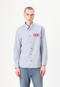 Zila un balta svītruota krekla ar pogām, ar punktētu apkakli, ar sarkanu logo kreisajā krūtīs. Kokvilnas audums, garas piedurknes.