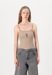 Lys brun ribbet tanktop med tynne stropper, med svart kaktusbroderi i midten, sammen med grå vide bukser.