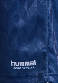 Marinblå sportströja med ett texturerat chevronmönster, tillverkad av andningsbart tyg, med "hummel SPORTSWEAR"-logotypen i vitt längst ner.