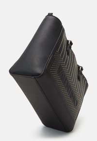 Black leather bag with gold-tone studs in a zigzag pattern, featuring a sturdy rectangular shape and embossed branding on the side.