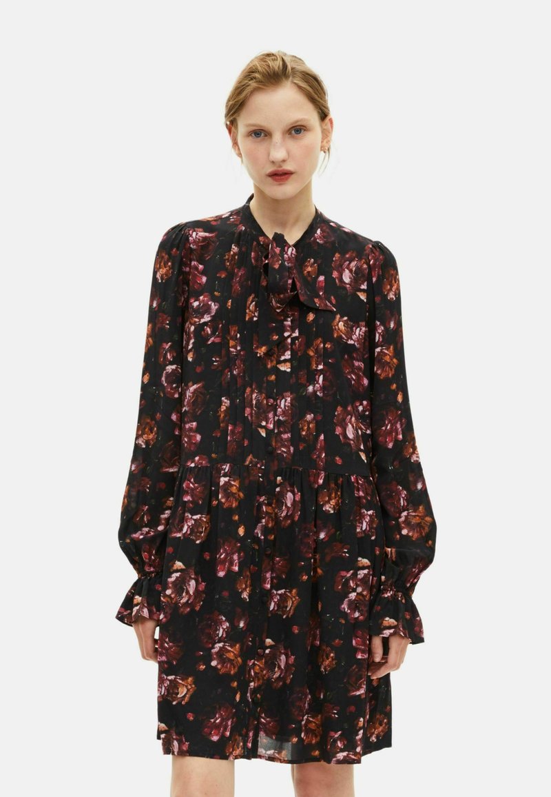 Schwarzes Blumen Kleid mit langen Ärmeln, gestuften Manschetten und einem Schleifenkragen. Es hat burgunderrote und braune Blumenmuster auf einem transparenten Stoff.