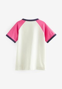 Kortærmet t-shirt med en hvid krop og lyserøde raglanærmer samt marineblå krave og kant. Tofibers stoffet har en glat tekstur.
