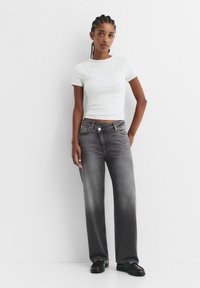 Sivé vysoké džínsy so zoslabeným dizajnom a piatimi vreckami, v kombinácii s svetlosivým priliehavým tričkom. Jednoduchý, ležérny vzhľad.