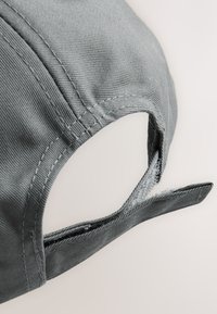 Graue Baseballkappe mit gebogenem Schirm, gefertigt aus strukturiertem Stoff, mit einem verstellbaren Klettverschlussriemen für eine individuelle Passform.