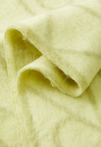 Tissu en laine doux de couleur jaune clair, avec une texture fine, présentant des bords enroulés et une finition subtilement légèrement duveteuse.