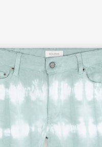 Vaqueros tie-dye en verde claro con superficie texturizada, que presentan un cierre de botón metálico y una etiqueta que dice "SCALPERS" en la cinturilla.