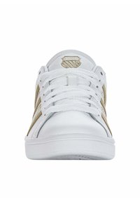 White sneakers with gold accents, round toe, flat sole, fabric upper, lace-up design, and embroidered logo on the tongue.