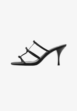 Sort højhælet sandal med slanke stropper, spidse tå og en slank hæl. Fremstillet af glat syntetisk materiale med en blank overflade.