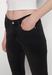 Svarta jeans i denim med slim fit, med en frampocket, metallknappstängning och subtila sömnadsdetaljer.