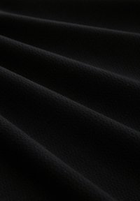 Tissu noir texturé avec de douces ondulations, présentant une surface lisse et uniforme. Le matériau a un léger éclat et est léger.