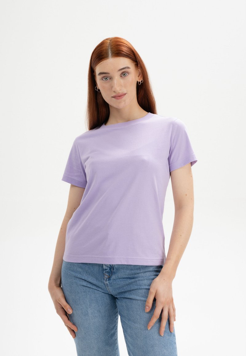Lichtpaarse, kortgecollarde t-shirt van katoen, met een ronde halslijn en een relaxed fit, gecombineerd met lichtblauwe jeans.