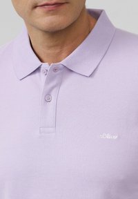 Lila polo shirt met korte mouwen van textuurstof. Voorzien van een knoopsluiting en een geborduurd "s.Oliver"-logo op de borst.