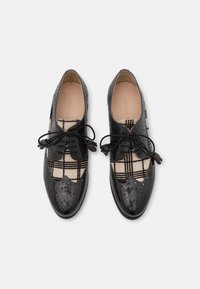 Scarpe nere in pelle con parte superiore in tessuto a quadri, caratterizzate da dettagli brogue, punte rotonde e lacci neri. Materiali lisci e testurizzati combinati.