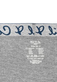 Tejido gris con texto bordado en navy en la cinturilla. La etiqueta de cuidado indica 95% algodón, 5% elastano. Talla marcada como M.