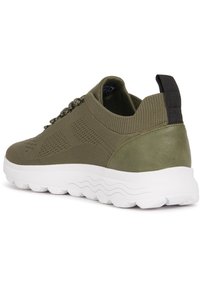 Sneaker verde oliva con tomaia in maglia, dettagli texture e tallone in pelle liscia. Presenta una suola bianca e ammortizzata e un tassello per il sollevamento.