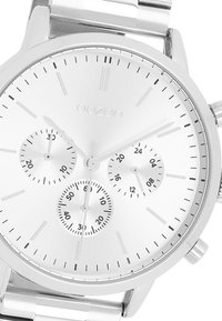 Montre en acier inoxydable avec un cadran argenté, trois sous-cadrans pour le suivi des minutes et des heures, fines marques horaires et bracelet en métal poli.