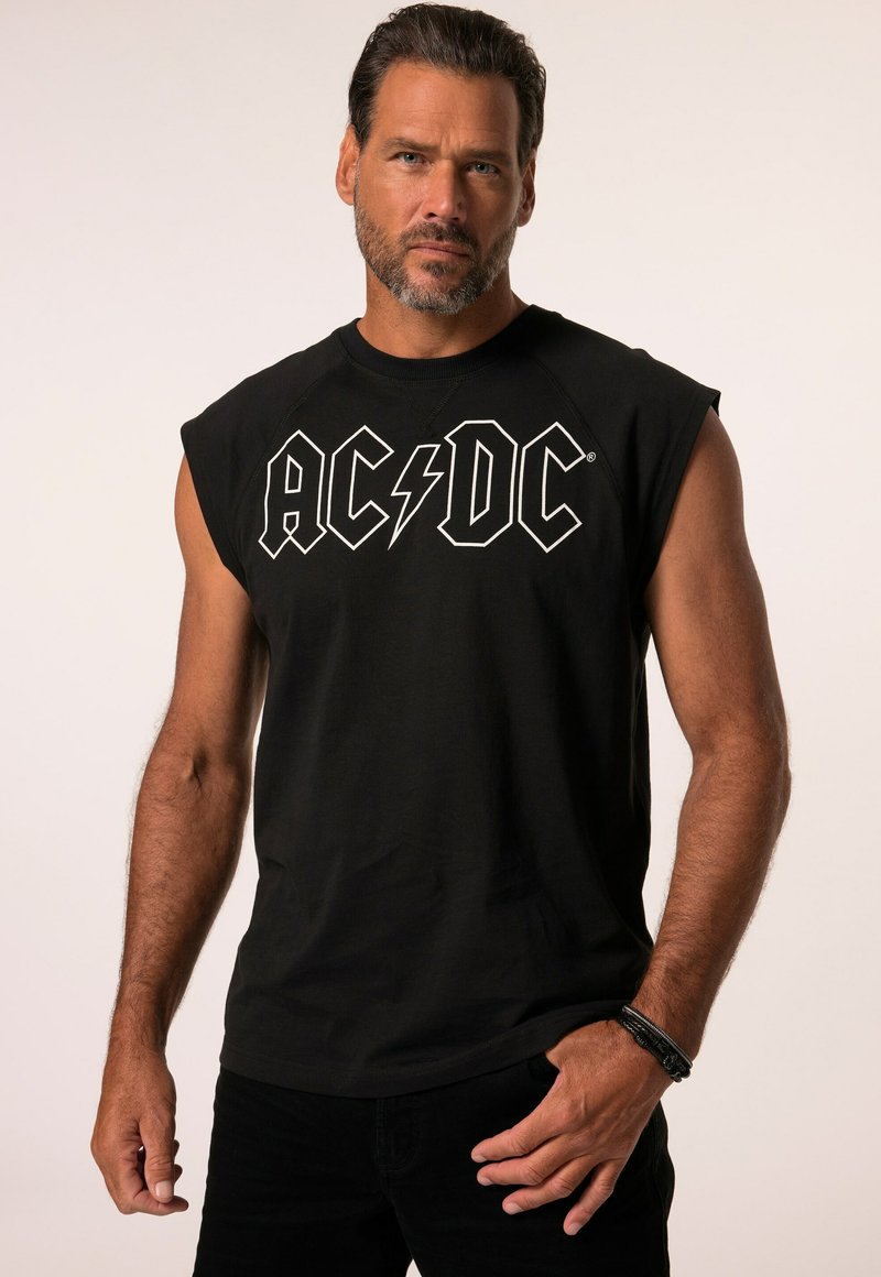 Zwarte mouwloze T-shirt gemaakt van katoen, met witte "AC/DC" logo met een bliksemflits, gecombineerd met donkere spijkerbroek en een armband.