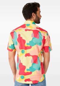 Camicia a maniche corte in colori vivaci con motivi astratti in forme rosse, verdi, gialle e pesca, insieme a strisce e pois.