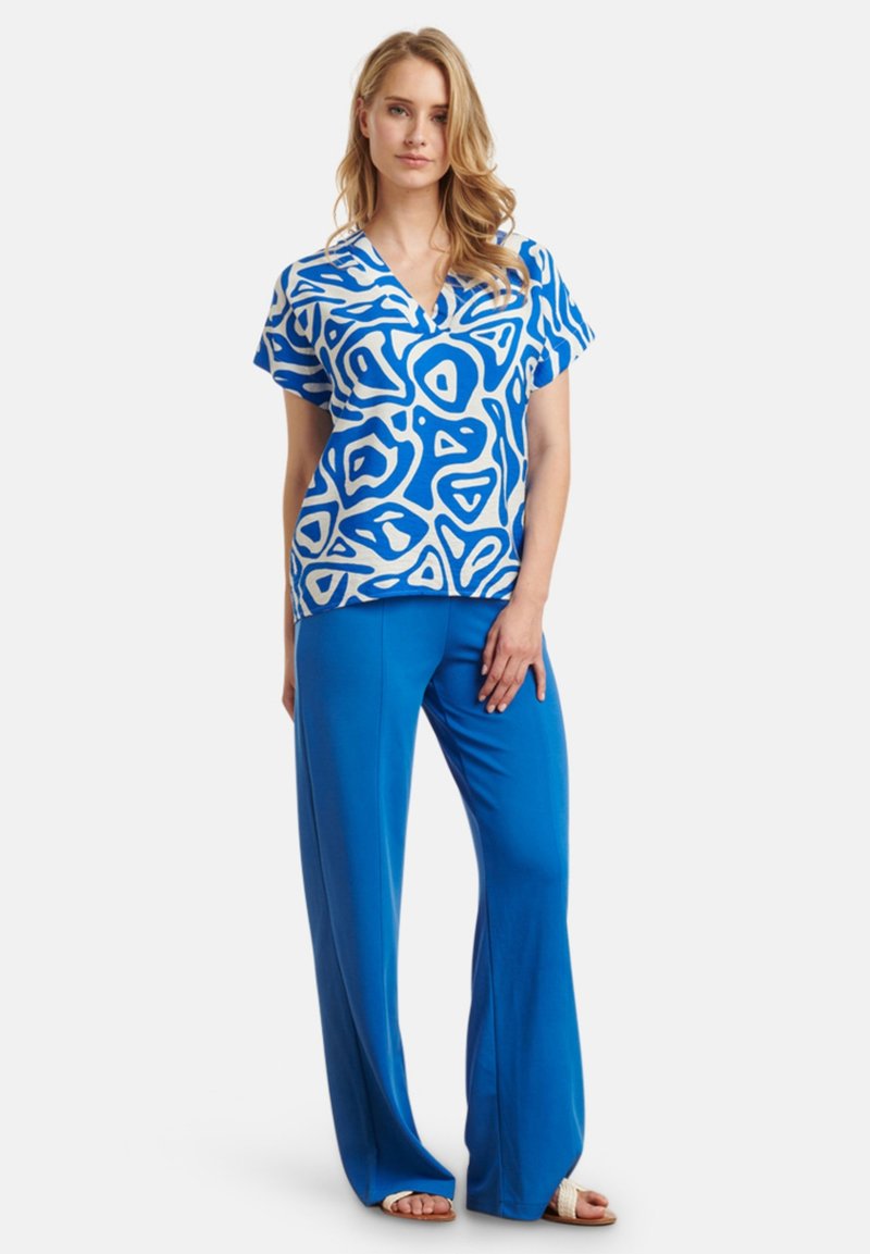 Blue patterned top with short sleeves, featuring organic shapes. Paired with solid blue, wide-leg pants. Both made from lightweight fabric.