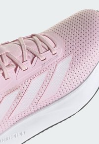 Różowe buty sportowe z oddychającego materiału siatkowego, teksturowaną powierzchnią, białymi akcentami w postaci trzech pasków oraz lekką podeszwą.