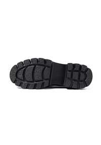 Semelle de chaussure en caoutchouc noir avec surface texturée. La semelle présente des motifs en relief et des rainures pour l'adhérence. Bout arrondi et talon plat.