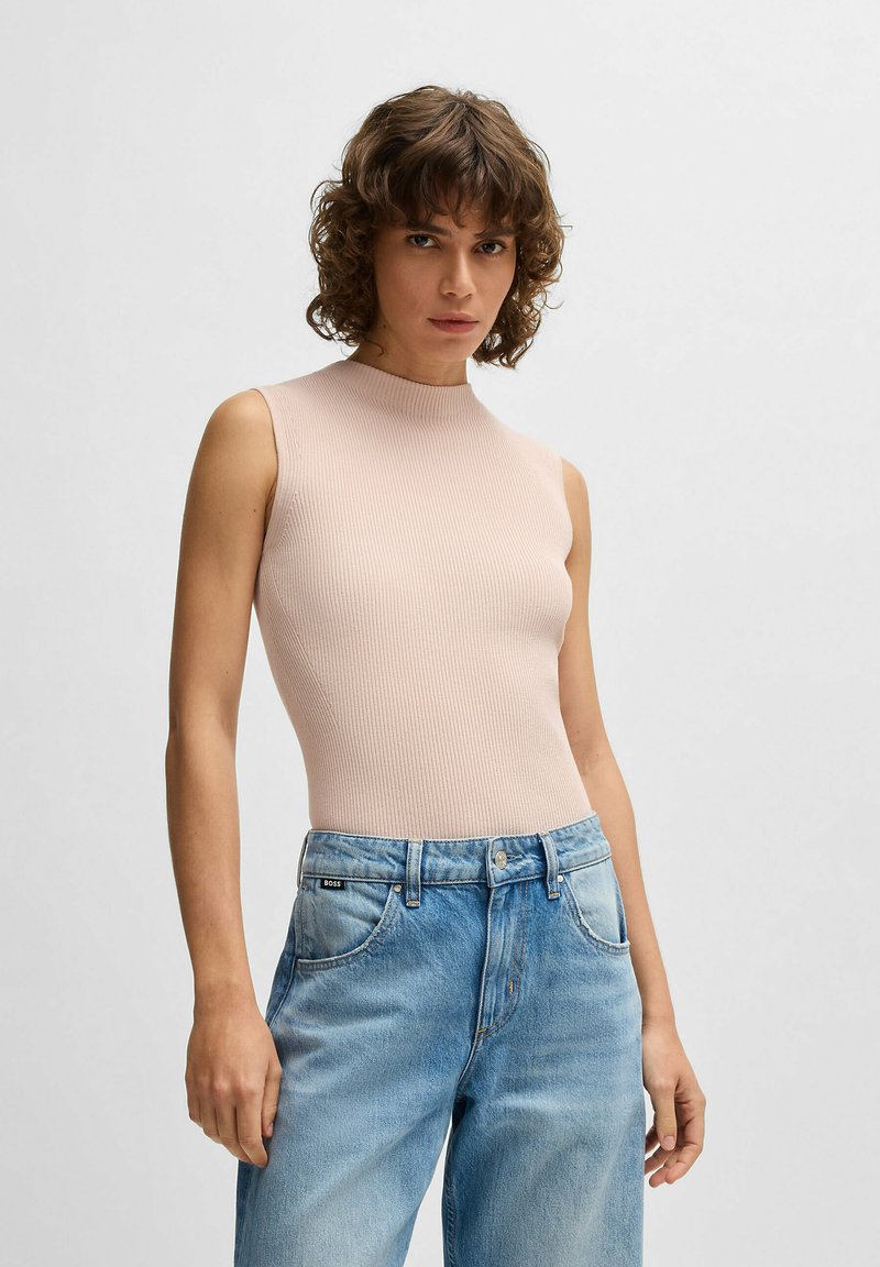 Ribbed, sleeveless top in light pink, featuring a high neck. Paired with light blue denim jeans with a faded finish and five-pocket design.