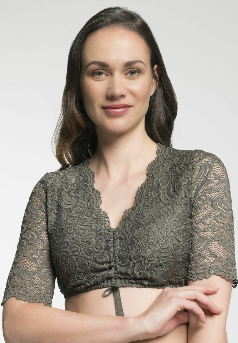 Olivgrünes Spitzen-Crop-Top mit kurzen, halbtransparenten Ärmeln, gewellten Kanten und einer Kordelzug-Frontöffnung. Texturiertes Blumenmuster über die gesamte Fläche.