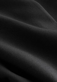 Zwarte stof met een gladde textuur, die een subtiele glans en zachte plooien vertoont. Het materiaal lijkt lichtgewicht en uniform van kleur.