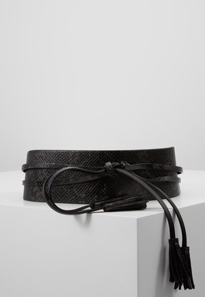 Czarny teksturowany pasek taliowy z owijanym wiązaniem i końcami z frędzlami, prezentowany na białej powierzchni na szarym tle.