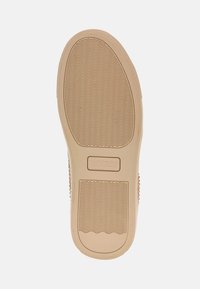 Suola di gomma beige per sneaker con scanalature testurizzate per una buona presa, caratterizzata da un logo in rilievo e un profilo liscio e arrotondato.