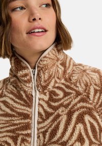 Bruine en crèmekleurige fleece jas met een gestructureerd spiraalpatroon, voorzien van een hoge kraag en een ritssluiting aan de voorkant. Zacht, pluizig materiaal.
