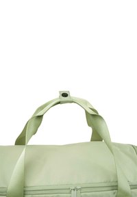 Bolsa de viaje verde claro de tela suave, con asas dobles y cierre con cremallera. Textura lisa con bordes redondeados y diseño minimalista.