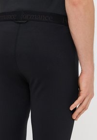 Black performance leggings with a smooth texture, featuring a wide waistband embossed with the word "performance" in dark lettering.