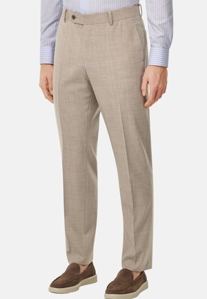 Hellbeige maßgeschneiderte Hose aus strukturiertem Stoff, mit flachem vorderen Schnitt, seitlichen Taschen und Gürtelschlaufen. Begleitet von braunen Slippern.