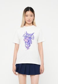 White cotton t-shirt featuring a whimsical purple bat graphic holding a heart, with accents of stars and a crescent moon.