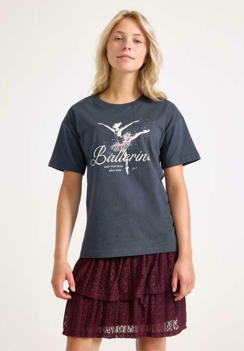 Sort t-shirt med en ballerina grafik i pink og hvid, parret med en lagdelt burgunder blonde nederdel, der fremviser ruffles og delikat tekstur.