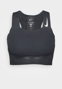 Černá sportovní podprsenka se širokými ramínky, s perforovanou texturou a reflexním logem na levém rameni. Design z hladké látky.