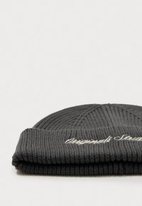Gebreide beanie in donkergrijs met een geribbelde structuur. Beschikt over een omgevouwen manchet met witte geborduurde tekst. Eenvoudig, snug fit ontwerp.