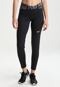 Leggings de sport noirs avec une taille haute portant "Nike Pro" en texte gris. Comprend un petit logo Nike blanc sur la cuisse gauche.