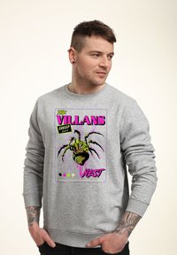 Grå sweatshirt med en grafisk design av en spindel och text i levande rosa och grönt. Ribbad mudd och rund hals.