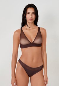 Conjunto de sujetador y bragas a juego en color marrón, hecho de un material transparente y suave. El sujetador presenta un diseño de escote en V con tirantes anchos y mínimo hardware.