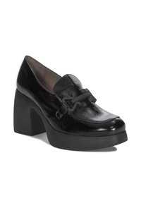 Zapato de estilo mocasín de cuero negro con un tacón grueso. Presenta una parte superior texturizada y un acento decorativo de hardware en la parte delantera.