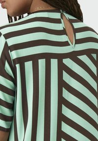 Short-sleeve top with a mint green and brown striped design. Features a round neck with a keyhole opening at the back. Soft texture.