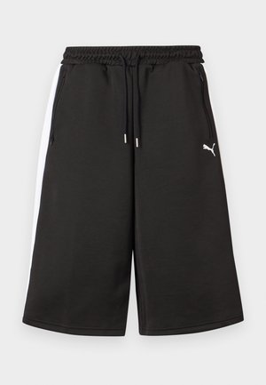 Juodos kelio ilgio sportinės kelnės su baltais šoninėmis juostelėmis, elastine liemene su raišteliais, užtrauktukais užsegamomis kišenėmis ir Puma logotipu ant dešinės šlaunies.