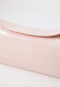 Rosa Clutch aus synthetischem Leder mit glatter Oberfläche, Klappenverschluss und dezenten Nähten entlang der Kante.
