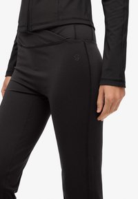 Czarne legginsy sportowe o miękkiej teksturze, z wysokim stanem i dekoracyjnym przeszyciem. Akcenty logo w okolicy bioder.