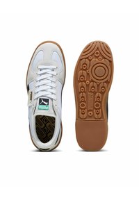 Sneaker bianche con materiali in rete e sintetici, caratterizzate da un pannello laterale nero, suola in gomma e logo Puma sulla linguetta e sulla suola.
