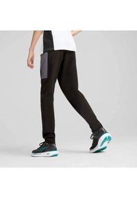 Zwarte sportbroeken met een grijze zijzak, slim fit en een elastische tailleband. Gecombineerd met contrasterende schoenen met turquoise accenten.
