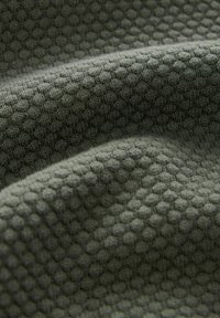 Strukturstoff in Dunkelgrün mit einem Wabenmuster. Es hat eine weiche, gestrickte Textur mit sichtbarem Tiefen- und Dimensionsgefühl.