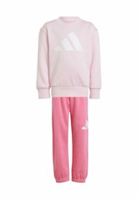 Sweatshirt rose et jogging assorti, fabriqués en tissu doux, avec un logo Adidas blanc sur le devant et sur la jambe gauche, avec des poignets côtelés.